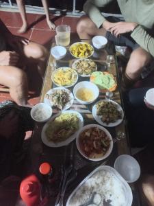 un grupo de personas sentadas alrededor de una mesa llena de comida en Homestay Hoàng Vũ, en Ha Giang