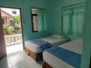 two beds in a room with green walls and a window at Charung Bungalows in Haad Rin