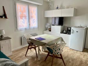 a kitchen with a table and chairs in a room at Sénane - Joli studio à 50m de la plage, parking in Courseulles-sur-Mer