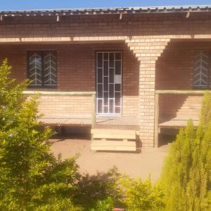 un bâtiment en briques avec deux fenêtres et deux bancs dans l'établissement Sunshinevibe guest house, à Kasane