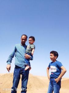 a man holding a child while standing in the sand at رحله تسوق الغردقه in Hurghada