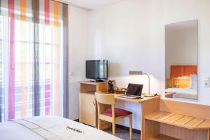 a hotel room with a bed and a desk with a laptop at acora Düsseldorf Living the City - Apartments in Düsseldorf