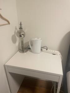 einem weißen Tisch mit einer Lampe und einer Tasse drauf in der Unterkunft Hechtplatz Hotel - Self Check-in in Zürich