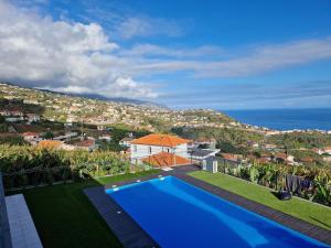 a house with a swimming pool and a view of the ocean at Vila Inanda in Ponta do Sol