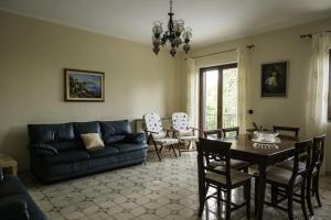 sala de estar con sofá, mesa y sillas en Villa Sara sull'etna con Piscina, en Viagrande