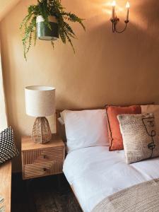 a bedroom with a bed with a lamp and a plant at Boutique country hideaway ‘Jacks Cottage’ in Diddlebury