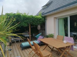a patio with a wooden table and chairs on a deck at Tous à l'ouest in Combrit
