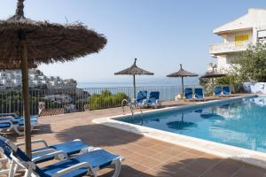 a swimming pool with chairs and umbrellas and the ocean at Nueva Vista 2º-4 in Cullera