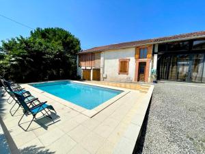 a swimming pool with a chair and a house at Maison de campagne chaleureuse in Mun