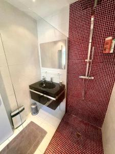 a bathroom with a red tiled shower and a sink at Maison de campagne chaleureuse in Mun