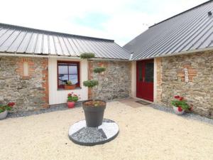 a brick house with a red door and a flower pot at Au tour des sens in La Jumellière