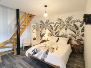 a bedroom with a bed with a palm mural on the wall at Au tour des sens in La Jumellière