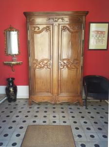 une grande armoire en bois dans une pièce aux murs rouges dans l'établissement Le Clos Saint-Germain, à Rugles