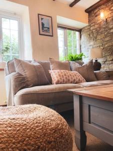 a living room with a brown couch and a stone wall at Boutique country hideaway ‘Jacks Cottage’ in Diddlebury