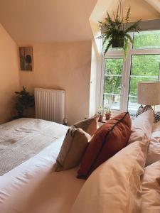 a bedroom with a large bed with pillows and a window at Boutique country hideaway ‘Jacks Cottage’ in Diddlebury