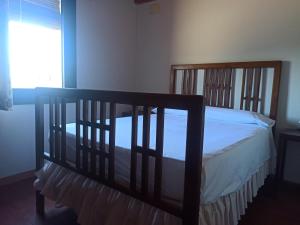 1 dormitorio con cama con marco de madera y ventana en El Molí de Cal Pastisser, en Avellanes