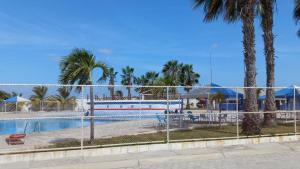 a swimming pool behind a fence with palm trees at Villa marina, santa elena in Santa Elena