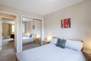 1 dormitorio con cama blanca y espejo en The Kelvin - Peaceful West End River View Property, en Glasgow