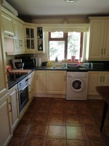 a kitchen with a sink and a washing machine at Crover Cottage Twin Room with Lake View in Mountnugent