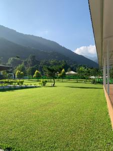 a large grassy field with a mountain in the background at Star & Moon GUEST HOUSE in Puli