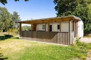 a small house with a wooden fence in a yard at Mobile home in Sjöared in Markaryd