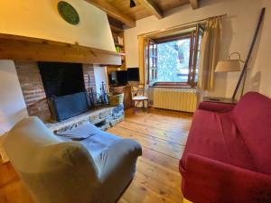 ein Wohnzimmer mit einem roten Sofa und einem Kamin in der Unterkunft Pleta de Ordino 55 Casa Rústica hasta 6 personas in Ordino
