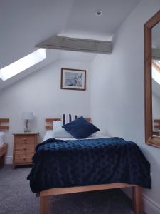 a bedroom with a bed with a blue blanket and a mirror at Cheerful Fisherman,s Cottage in St Ives