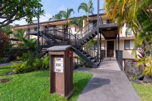 a building with a staircase and a sign in the grass at Country Club Villas 124 in Kailua-Kona