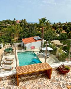 a swimming pool with a bench and a house at Palm View Guesthouse, adults only in Luz