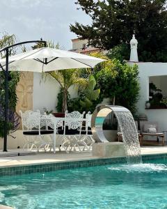 een zwembad met een parasol en een fontein bij Palm View Guesthouse, adults only in Luz