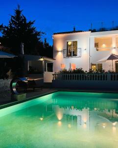 uma piscina em frente a uma casa à noite em Palm View Guesthouse, adults only na Praia da Luz