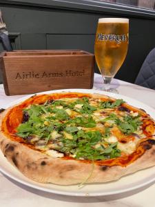 a pizza on a table with a glass of beer at Airlie Arms Hotel in Kirriemuir