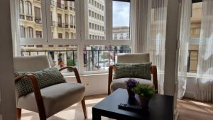 a living room with two chairs and a table and windows at IMEDA REYES CATÓLICOS in Granada