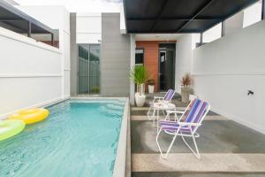 a house with a pool with chairs and a table at Sunny Afternoon Pool Villa ~ Hua-Hin in Hua Hin