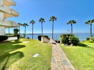 a walkway next to the ocean with palm trees at Marbella del Mar II Beachfront- EaW Homes in Marbella