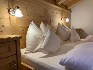 una cama con almohadas blancas en una habitación en Agriturismo Maso Larciunei, en Selva di Val Gardena