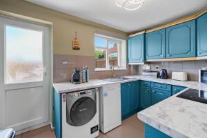 a kitchen with blue cabinets and a washing machine at BridgeCity Cheerful 3 bedroom home in Nuneaton in Nuneaton