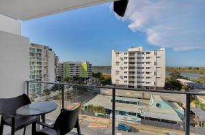 a balcony with a table and chairs and some buildings at Airtrip Apartments on River Street, Mackay in Mackay