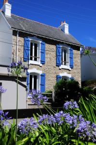 una casa con persianas azules y flores púrpuras en Nouveau : maison à 50 m de la plage, en Larmor-Plage