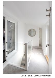 a glass staircase in a white room with a mirror at Dunster Studio Apartment in Dunster