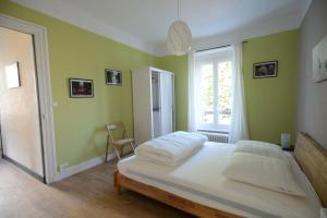 1 dormitorio con paredes verdes y 1 cama con sábanas blancas en Nouveau : maison à 50 m de la plage, en Larmor-Plage