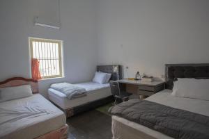 a room with two beds and a desk and a desk at Kallista Homestay in Banyuwangi