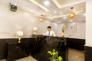 a man standing at a counter in a hotel lobby at Hotel Earth in New Delhi