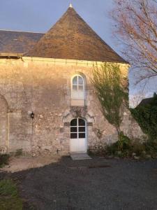 ein altes Steingebäude mit einer weißen Tür und einem Turm in der Unterkunft La Chapelle in Chanceaux-sur-Choisille