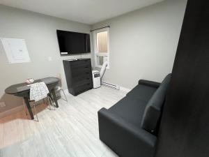 a living room with a couch and a table and a television at Le Centre-Ville in Rouyn-Noranda