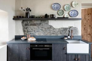 cocina con fregadero y pared de piedra en Gate Lodge@White Strand en Miltown Malbay
