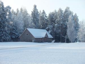 a barn in the snow with a field and trees at Roosu Talu Accommodation in Sulbi +11 photos