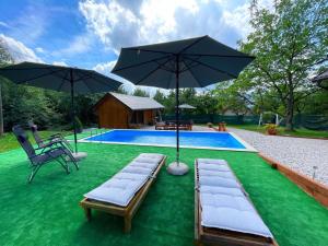 a pool with two chaise lounges and two umbrellas at Hellena in Sarajevo