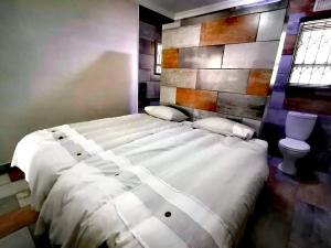 a bedroom with a large white bed and a toilet at Peace Cottages Uvongo. in Uvongo Beach +213 photos