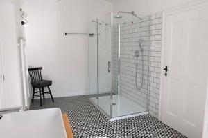 a bathroom with a glass shower with a chair at Beautiful 2bed apartment in the centre of Varazdin in Varaždin